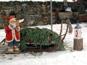 a santa claus standing next to a christmas tree at Les Chevreuils in Arvier