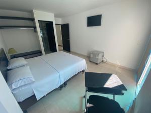 1 dormitorio con cama blanca y escritorio en Hotel Torres del Llano, en Yopal