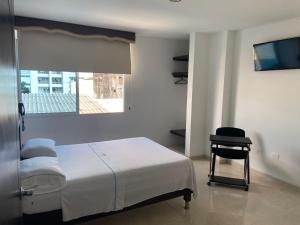 1 dormitorio con 1 cama, 1 silla y TV en Hotel Torres del Llano, en Yopal