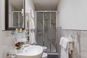 a white bathroom with a shower and a sink at Hotel Accademia in Florence