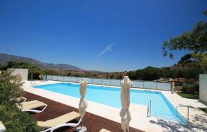 ein Pool mit zwei Liegestühlen und zwei Sonnenschirmen in der Unterkunft La Cala Golf Resort 3 Bed Apt - sleek corner plot in La Cala de Mijas