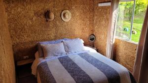 a bedroom with a bed with a striped blanket and a window at Espectacular cabaña campestre con granja in Zipaquirá