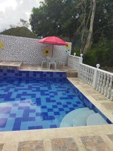 einen Pool mit einem roten Regenschirm und einem Tisch mit in der Unterkunft FINCA CAMPESTRE EL MIRADOR VIOTA in Viotá