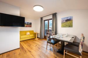 a living room with a table and a yellow couch at Wohn-Leben Altenmarkt Apartments in Altenmarkt im Pongau