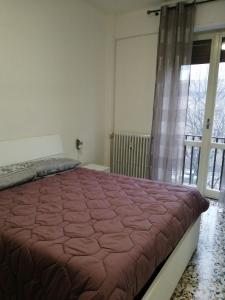 um quarto com uma cama e uma grande janela em Casa arcobaleno em Asti