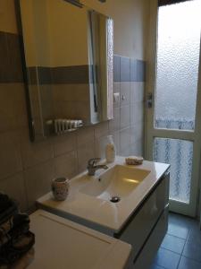 uma casa de banho com um lavatório, um espelho e uma janela em Casa arcobaleno em Asti