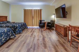 um quarto de hotel com duas camas e uma secretária e uma televisão em Motel Roberval em Roberval