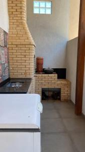 a kitchen with a brick fireplace in a room at Casa de Praia - Suítes in Arraial do Cabo