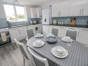 a kitchen with a table with plates and wine glasses at 21 Sandfield Road in Burry Port