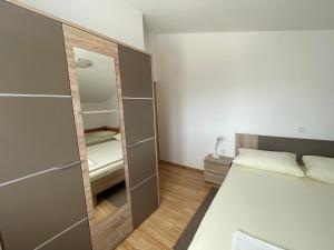 a small bedroom with a bed and a mirror at Petros Apartments Pag in Pag