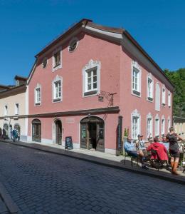 un grupo de personas sentadas en un banco frente a un edificio en das-hornsteiner, en Passau