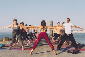 un gruppo di persone che fanno yoga sulla spiaggia di The Salty Pelican Beach Retreat a Monte Estoril