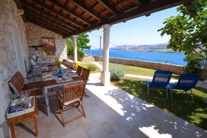 un patio con tavolo, sedie e vista sull'acqua di Holiday Home Fiola a Zubovići