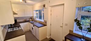 a small kitchen with white cabinets and a window at ✪ Spacious Luxury 2-bed w/ parking & garden in Killingbeck +8 photos