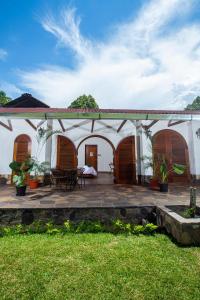 a white house with wooden doors and a patio at Lodge Casa de Campo "APU SAMAY" in Tarapoto