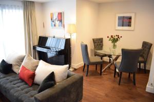 a living room with a couch and a table with a piano at Beautiful Modern 1 Bedroom Apartment in North London in London