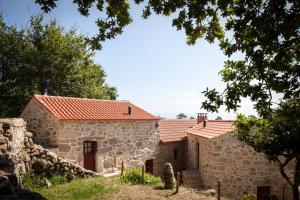 un ancien bâtiment en pierre avec des toits de tuiles rouges dans l'établissement Traços D'Outrora, à Vale de Cambra