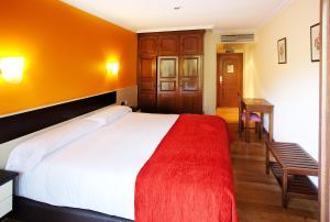 a bedroom with a large bed with a red blanket at Hotel Venta de Etxalar in Etxalar