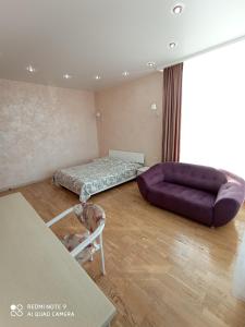 a living room with a purple couch and a bed at Apartment Frantsuzky Bulvar 60 G in Odesa