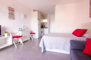a white bedroom with a bed and a kitchen at Benalmádena estudio JJupiter 250 m del mar con vistas al mar piscinas in Benalmádena