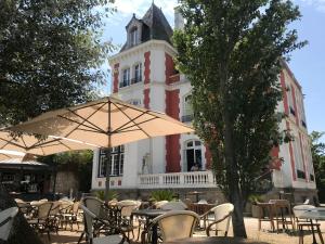 a group of tables with umbrellas in front of a building at TOUT A PIED ! T2 25m2 - Parking privé - Wifi in Larmor-Plage