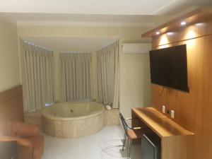 a bathroom with a tub and a television in it at Collina Hotel in Camapuã