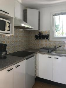 eine Küche mit weißen Schränken, einem Waschbecken und einem Fenster in der Unterkunft Appartement Rez de villa - Porte des Calanques in La Redonne