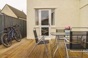 a patio with a table and chairs and a bike at Private deck with newly refurbished flat attached! in Cirencester