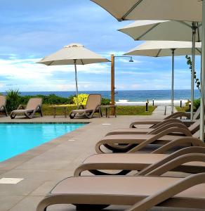 a row of chairs and umbrellas next to a swimming pool at Eastern Blue - Sea View Luxury Apartment in Poste Lafayette