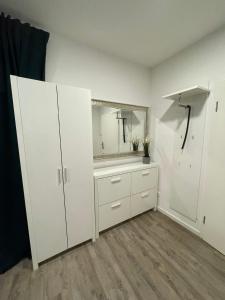 a white bathroom with white cabinets and a mirror at Feriendomizil an der Warnow in Rostock
