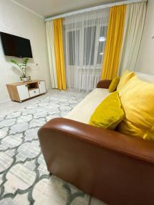 a bedroom with a bed with yellow pillows and a television at Апартаменты на Ахметова 6 in (( Turksib ))