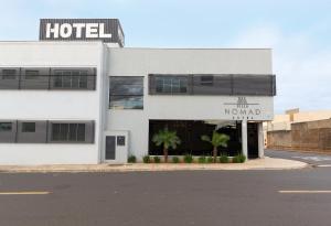 un bâtiment blanc avec un panneau d'hôtel et des palmiers dans l'établissement VILLA NOMAD HOTEL, à Uberaba