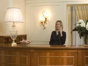uma mulher sentada numa secretária a falar ao telefone em Hotel Aberdeen em Roma