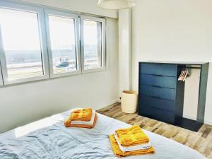 ein Schlafzimmer mit zwei Handtüchern auf einem Bett mit Fenstern in der Unterkunft Royal Palace Seaview Suite in Ostende