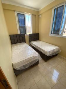 two beds in a room with two windows at Lovely 3-Bed Apartment in Mogadishu in Mogadishu