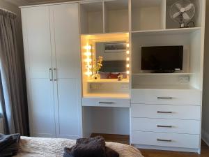 un centro di intrattenimento bianco con una televisione e un mobile bianco di Carraig House Cozy countryside apartment a Cavan