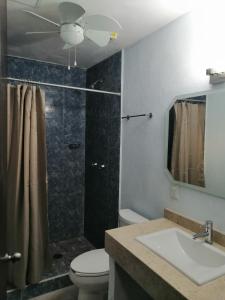 y baño con aseo, lavabo y ducha. en Habitaciones del Pacifico en Zihuatanejo