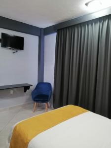 a bedroom with a bed and a blue chair at Habitaciones del Pacifico in Zihuatanejo