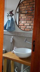 Casa dos Sonhos Hospedaria في Sêrro: حمام مع حوض أبيض ومرآة