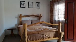 Cama de madera en habitación con ventana en Casa dos Sonhos Hospedaria, en Sêrro