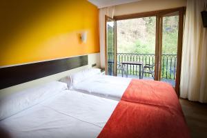 a bedroom with two white beds and a balcony at Hotel Venta de Etxalar in Etxalar