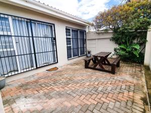 un patio de ladrillo con una mesa de picnic frente a una casa en Sea Breeze Manor - Gold Unit, en East London