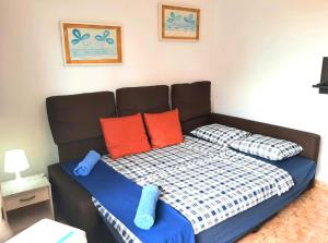 Bett mit orangefarbenen und blauen Kissen in einem Zimmer in der Unterkunft Perfectly located apartment with pool in Playa de las Americas