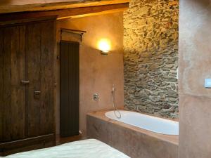 a bathroom with a bath tub and a stone wall at Foresteria Antica Farmacia in Cedegolo +20 photos