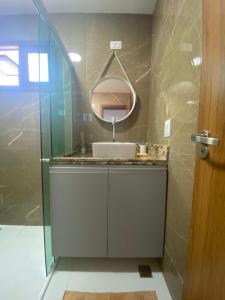 uma casa de banho com um lavatório e um espelho em Apartamento em Barra do Cunhaú em Barra do Cunhaú