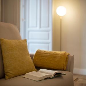 un libro abierto sentado en un sofá con una almohada y una lámpara en PETRONILA 1881, en Mérida