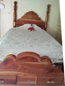a teddy bear sitting on top of a wooden bed at Lovely 1-Bed Cottage in St catherine Jamaica in Ewarton