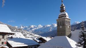 a large tower with a clock on top of it at La Pointe Percée in Le Grand-Bornand