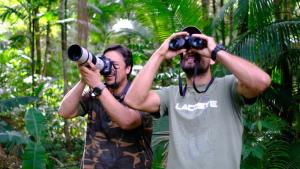 two men taking pictures with binoculars in the jungle at Pousada Salve Floresta in Tapiraí