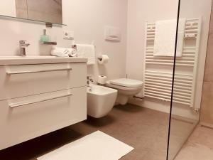 ein weißes Bad mit einem WC und einem Waschbecken in der Unterkunft Apartment Lilli mit Garagenstellplatz in Brixen